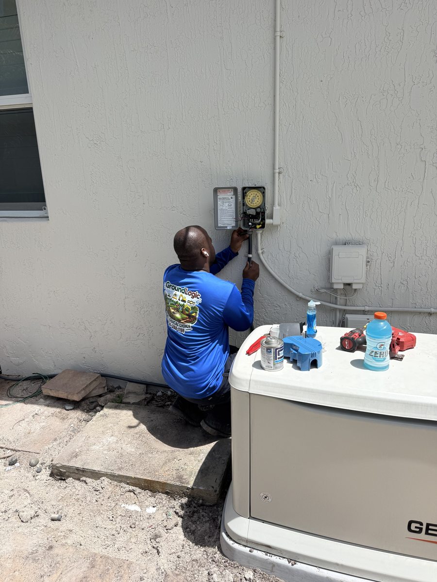 GroundLogic technician in branded uniform programming irrigation controller after pump relocation — Miramar, FL